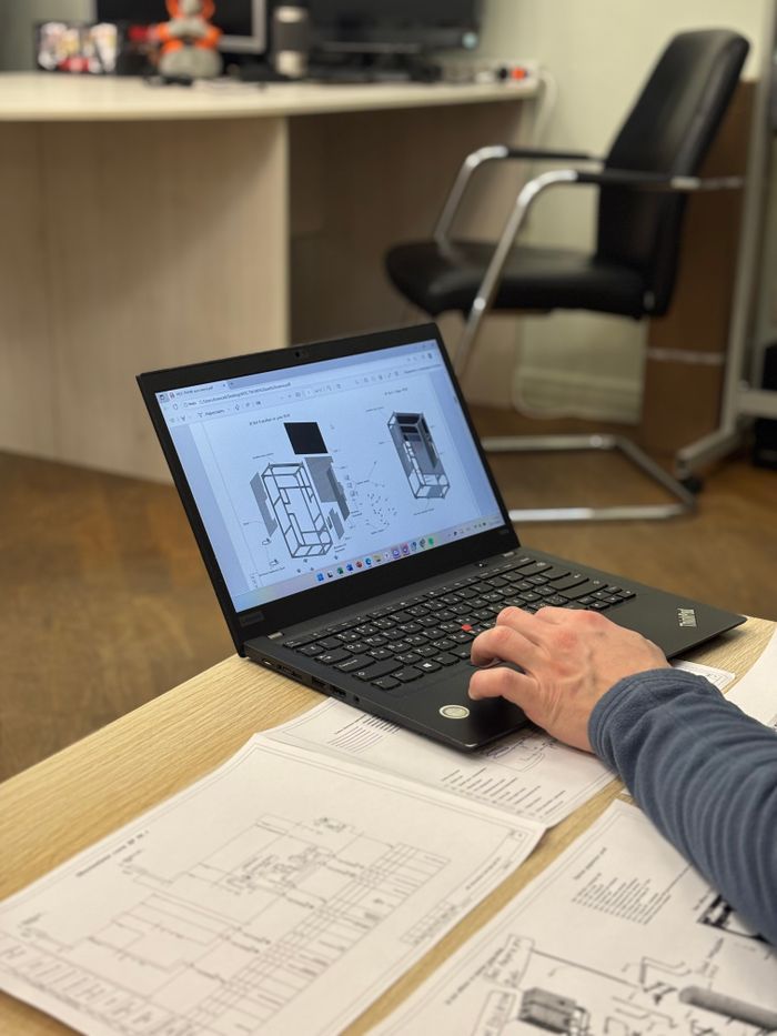 pexels-photo-34938429 An engineer reviews detailed blueprints on a laptop at an office desk.
